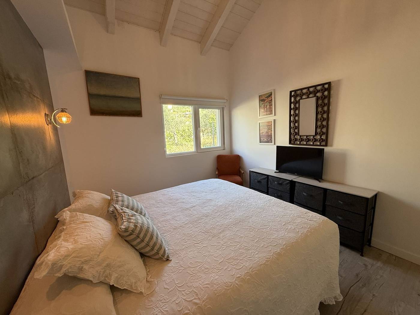 Dormitorio de matrimonio con televisión y sillón