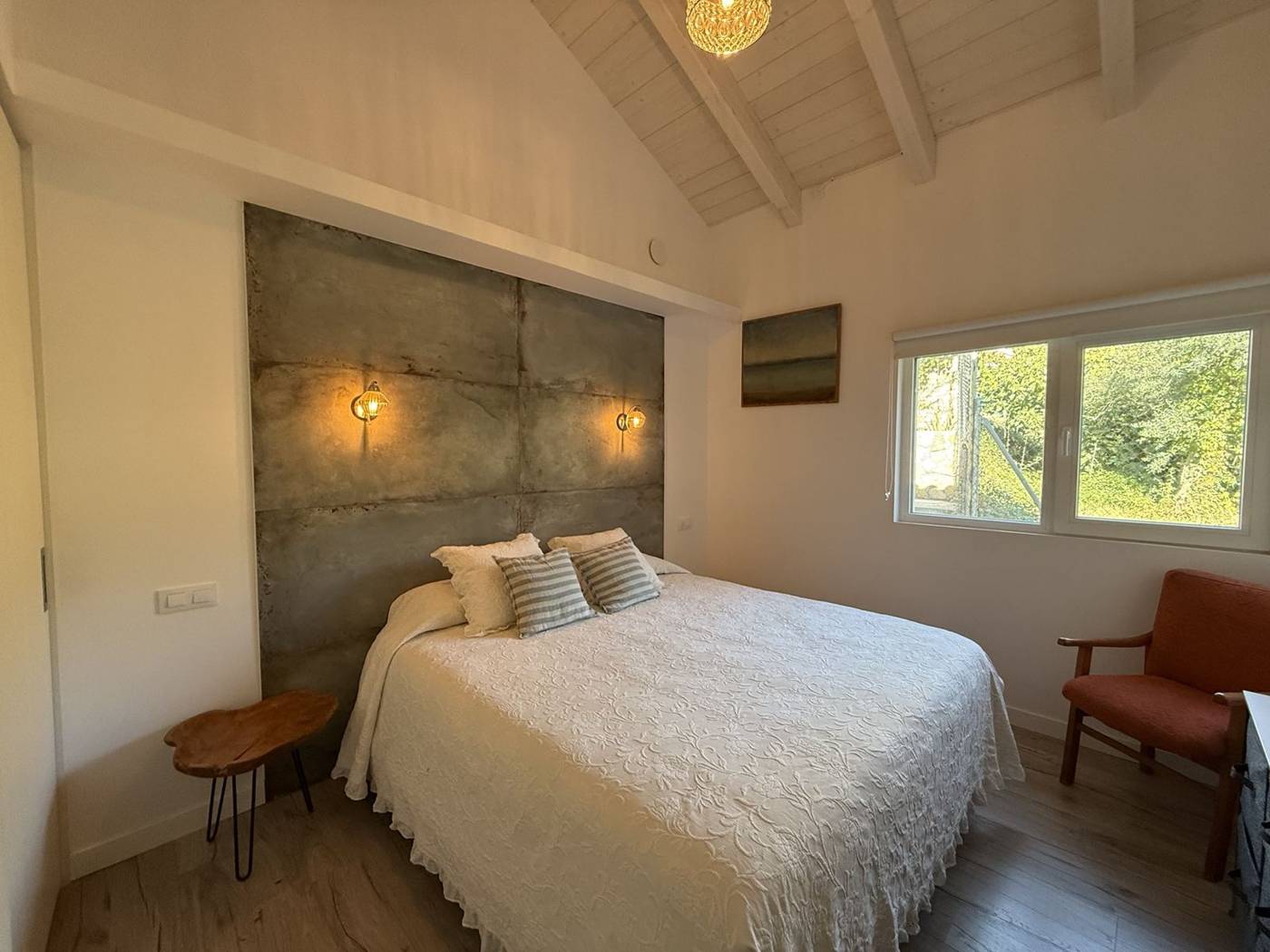 Dormitorio de matrimonio con cabecero de cemento y apliques