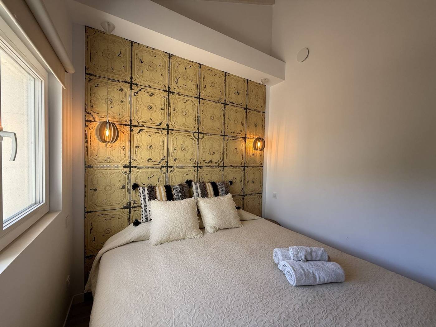 Dormitorio con cabecero de placas doradas