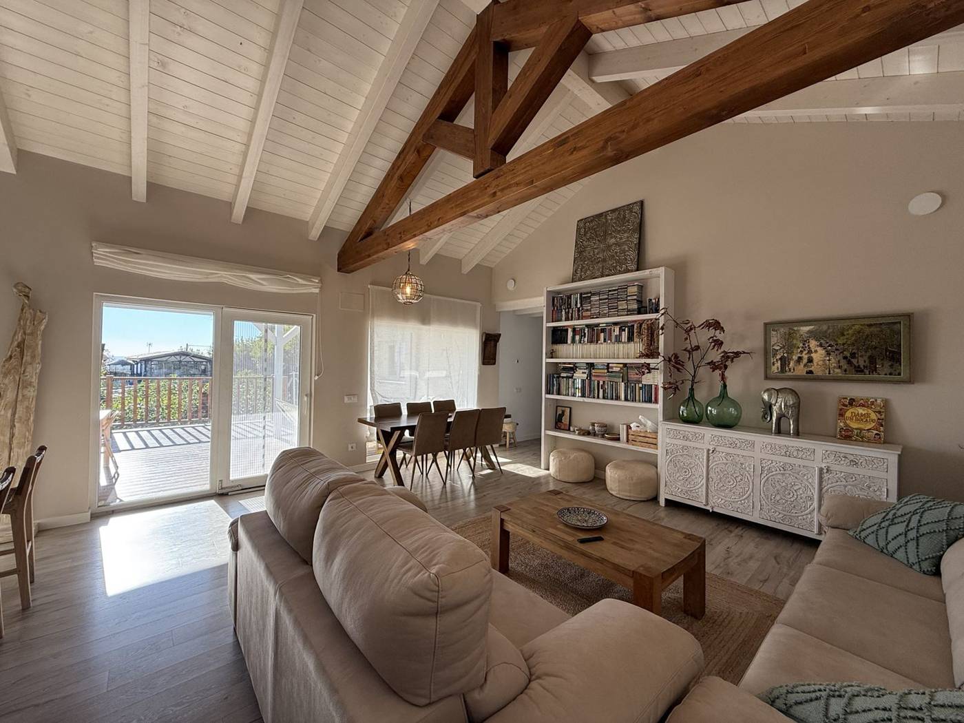 Salón de la Casa Rural La Pasivera con cercha de madera, sofás y salida a la terraza