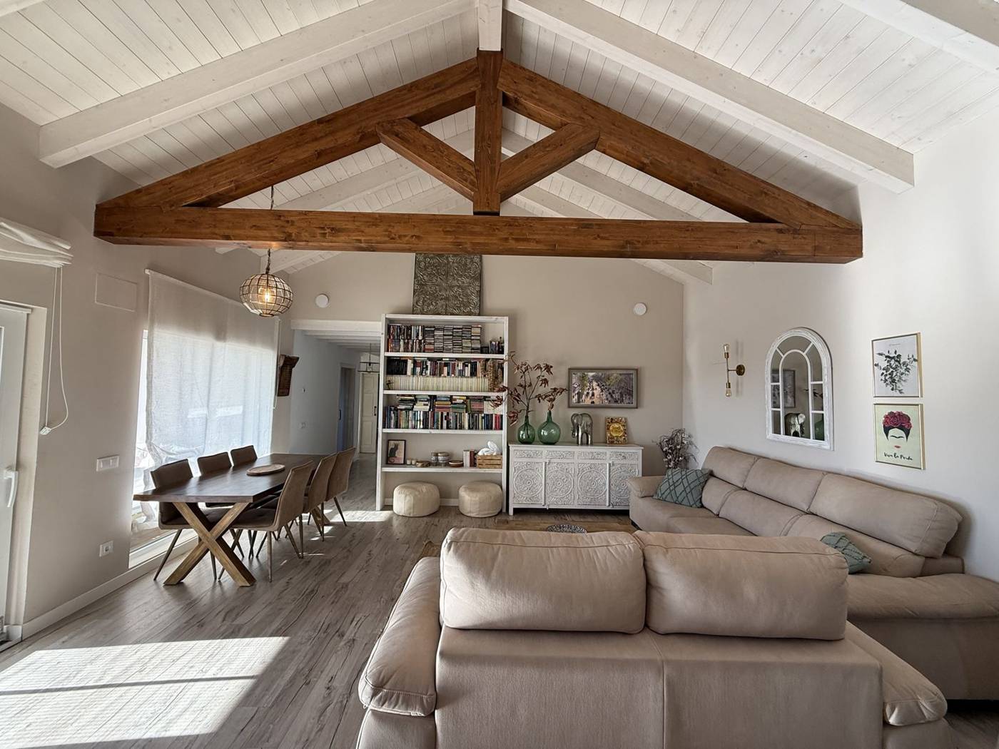 Salón con cercha de madera, sofás y mesa de comedor